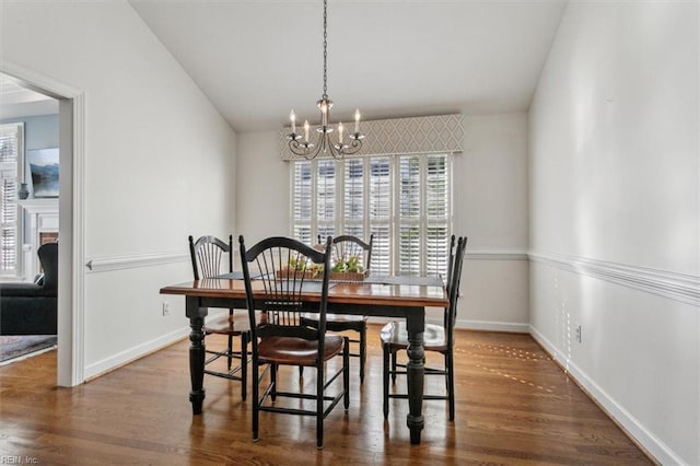 dining space featuring lofted ceiling, a notable chandelier, and wood finished floors