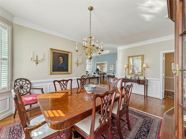 dining room with plenty of natural light, ornamental molding, wood finished floors, and wainscoting