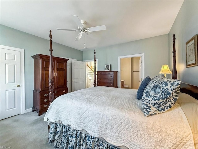 bedroom featuring baseboards, ensuite bathroom, a ceiling fan, and light colored carpet