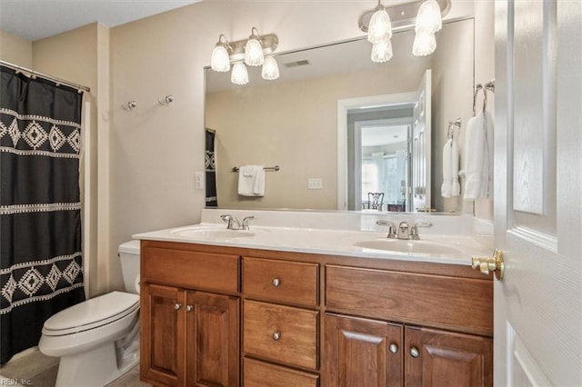 bathroom featuring toilet, double vanity, visible vents, and a sink