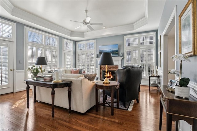 living area with a brick fireplace, a raised ceiling, and a healthy amount of sunlight