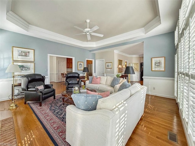 living area featuring visible vents, a tray ceiling, and wood finished floors