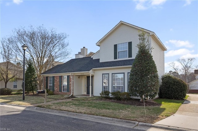 traditional home with a front yard, roof with shingles, a chimney, and brick siding