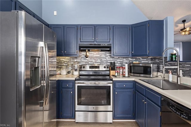 kitchen with blue cabinetry, appliances with stainless steel finishes, a sink, and under cabinet range hood