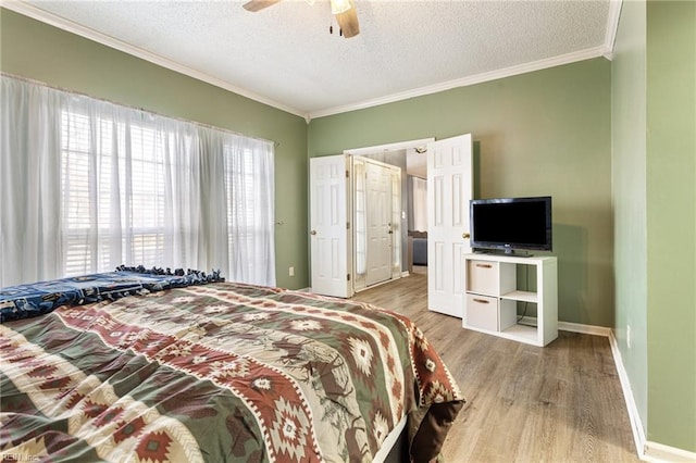 bedroom featuring baseboards, ceiling fan, ornamental molding, wood finished floors, and a textured ceiling