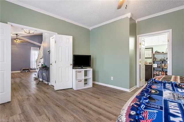 bedroom with crown molding, a textured ceiling, baseboards, and wood finished floors