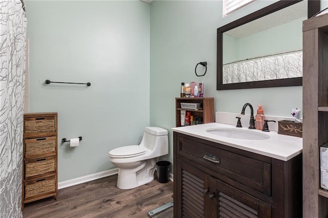 bathroom featuring baseboards, vanity, toilet, and wood finished floors