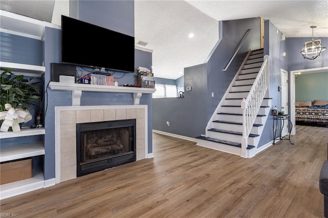 living area featuring stairs, a textured ceiling, and wood finished floors