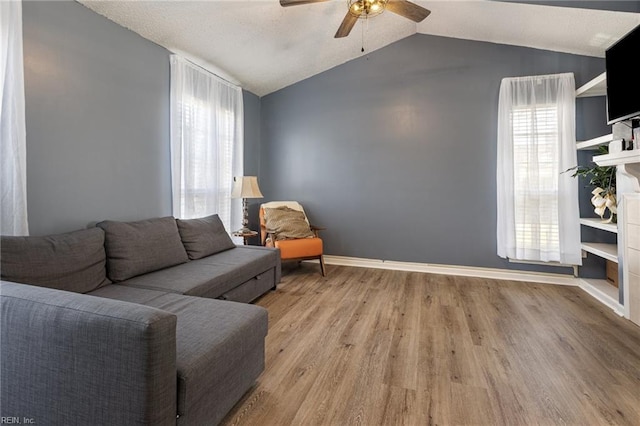 living area featuring lofted ceiling, plenty of natural light, baseboards, and wood finished floors