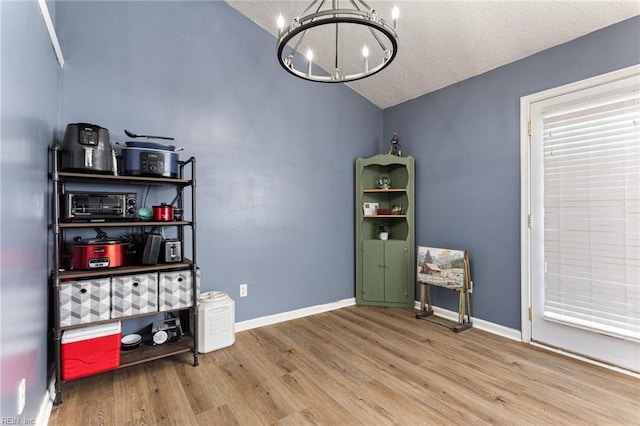 interior space featuring baseboards, wood finished floors, lofted ceiling, and a notable chandelier