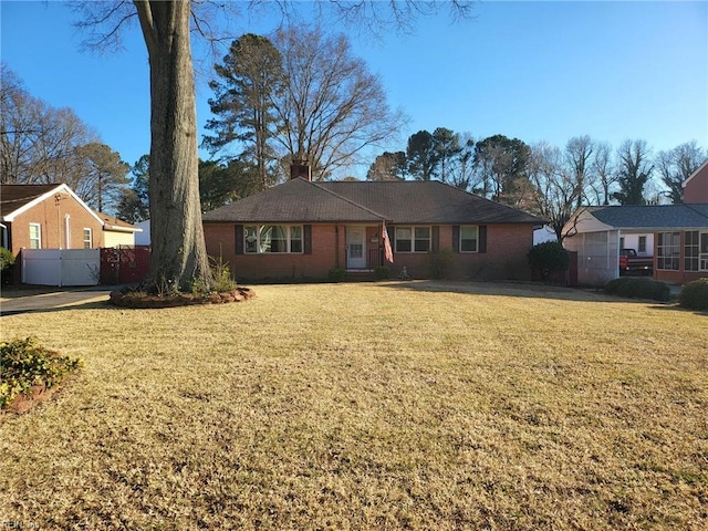 ranch-style home with a front lawn, a chimney, fence, and brick siding