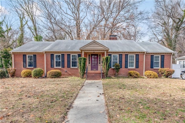 single story home with brick siding, a chimney, and a front lawn