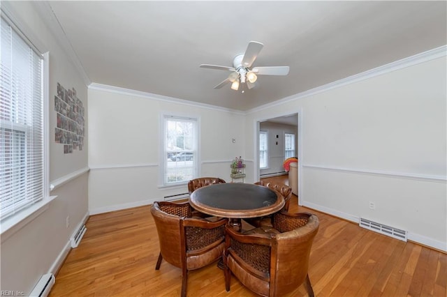 dining space with visible vents, light wood-style floors, ornamental molding, and a baseboard heating unit