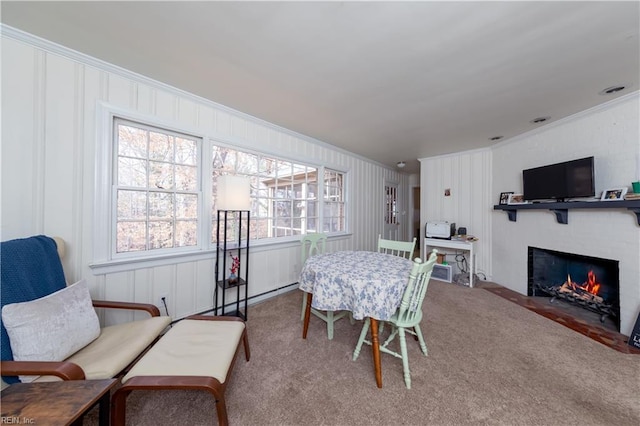 carpeted dining room with crown molding and a fireplace with flush hearth