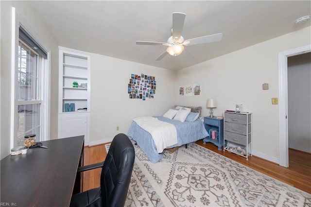 bedroom with ceiling fan, baseboards, and wood finished floors