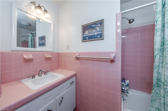 bathroom with a wainscoted wall, tile walls, vanity, and shower / bath combo with shower curtain