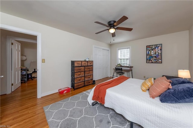 bedroom with a closet, baseboards, light wood-style floors, and a ceiling fan