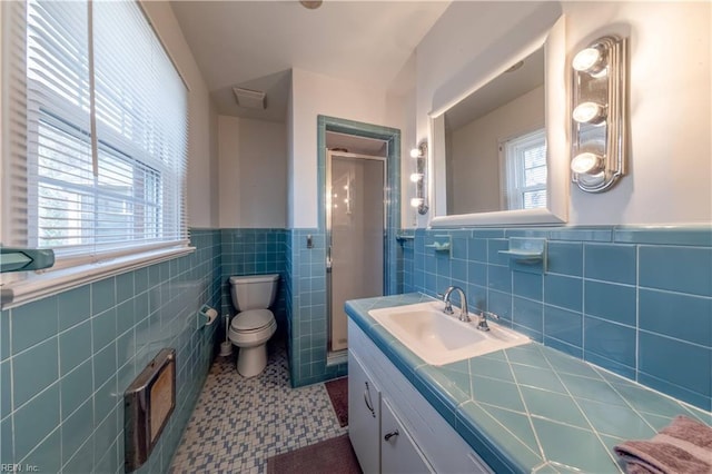 bathroom with a wainscoted wall, toilet, tile walls, a shower stall, and vanity