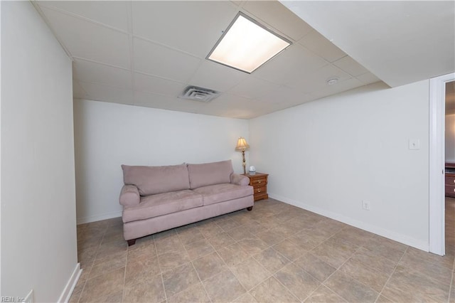 living area with visible vents, a paneled ceiling, and baseboards