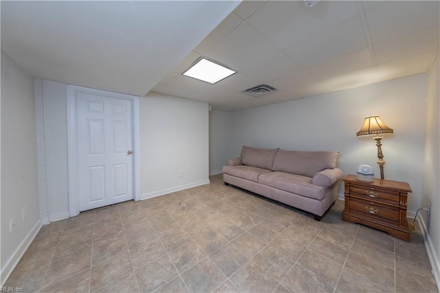 living area with baseboards, visible vents, and a paneled ceiling