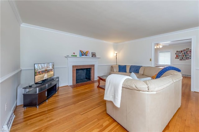 living area featuring a baseboard radiator, ceiling fan, light wood-style floors, crown molding, and a brick fireplace