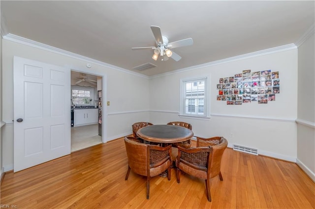 dining area featuring visible vents, ceiling fan, light wood-style floors, and ornamental molding