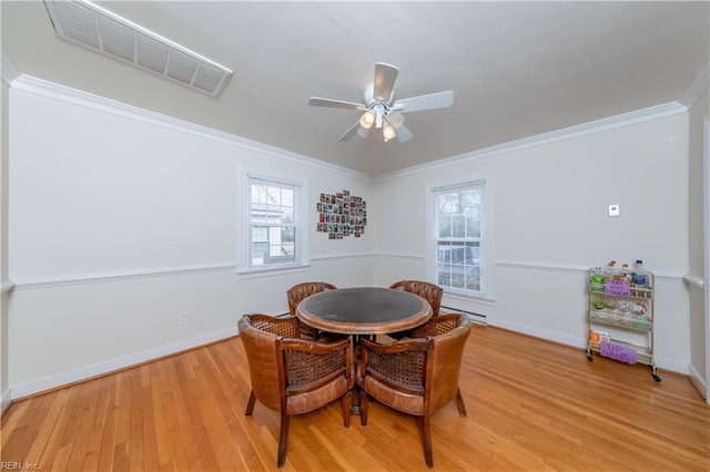 dining space with crown molding, plenty of natural light, wood finished floors, and visible vents