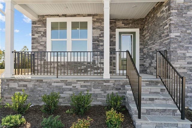 doorway to property featuring a porch and stone siding