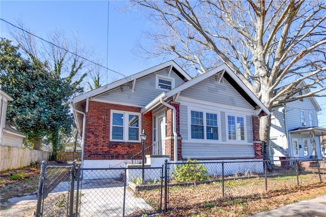 bungalow featuring a fenced front yard and brick siding