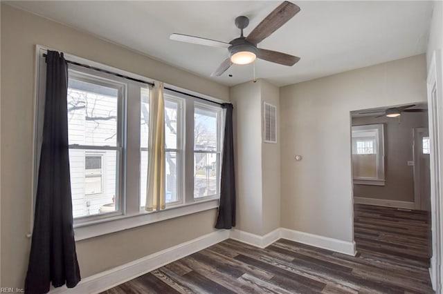 spare room featuring dark wood-style floors, visible vents, baseboards, and a ceiling fan