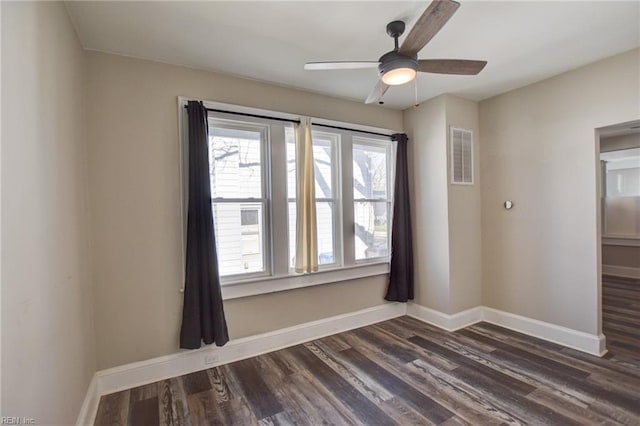 spare room with a ceiling fan, baseboards, visible vents, and dark wood-type flooring