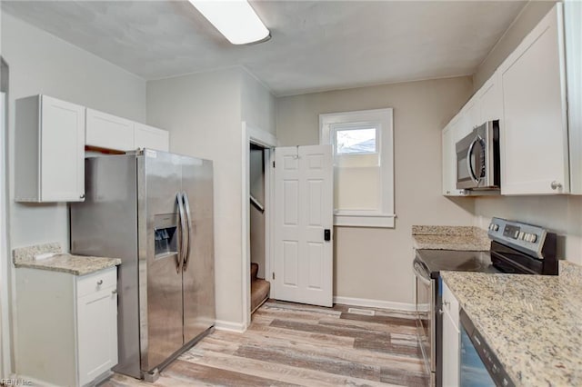 kitchen featuring stainless steel appliances, light wood finished floors, white cabinetry, and baseboards