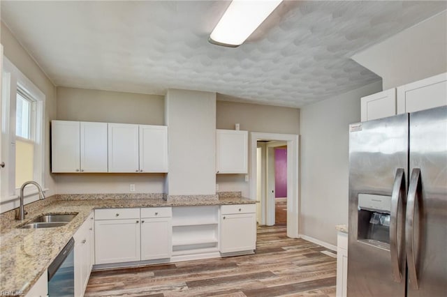 kitchen featuring light wood-type flooring, white cabinetry, stainless steel refrigerator with ice dispenser, and a sink