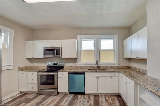 kitchen with stainless steel appliances, white cabinetry, a sink, and wood finished floors