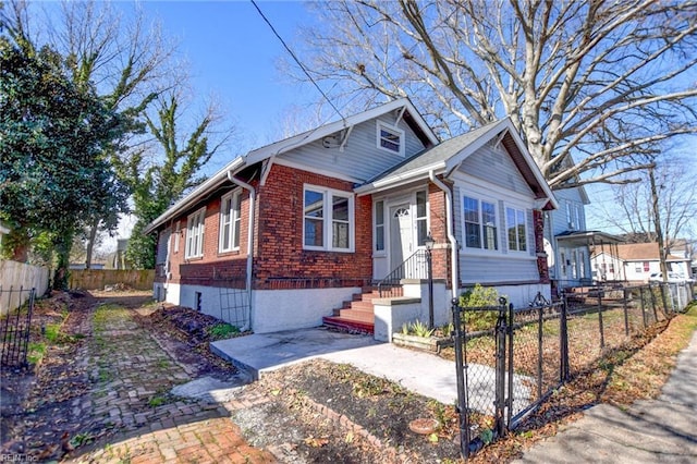 bungalow-style house featuring brick siding, a fenced front yard, and a gate