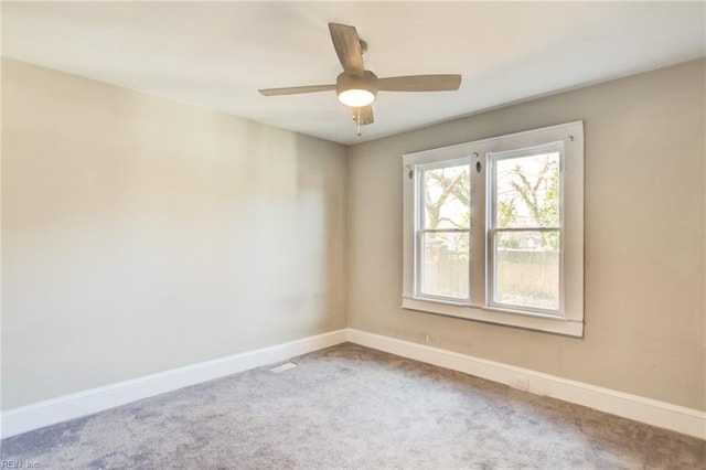 carpeted spare room featuring ceiling fan and baseboards