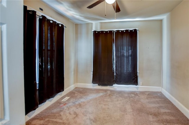 carpeted spare room featuring ceiling fan and baseboards