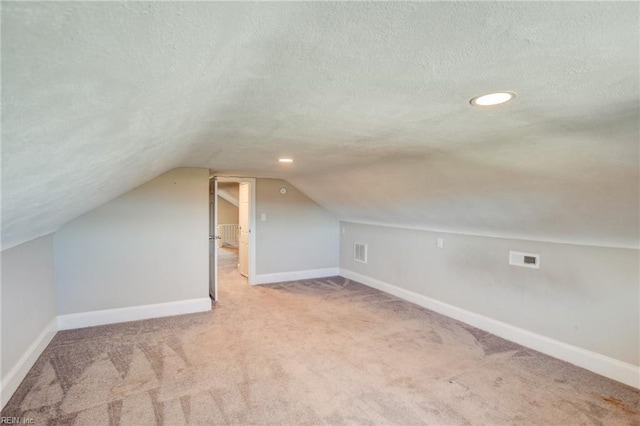 bonus room featuring baseboards, visible vents, lofted ceiling, a textured ceiling, and carpet flooring