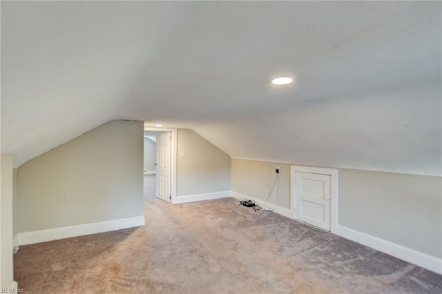 additional living space with carpet flooring, vaulted ceiling, and baseboards