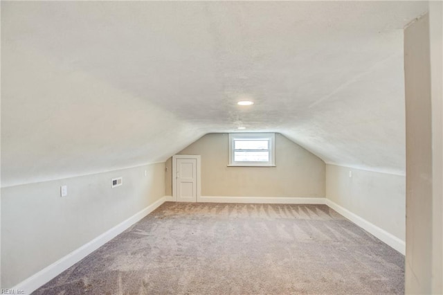 additional living space featuring lofted ceiling, a textured ceiling, carpet, and baseboards