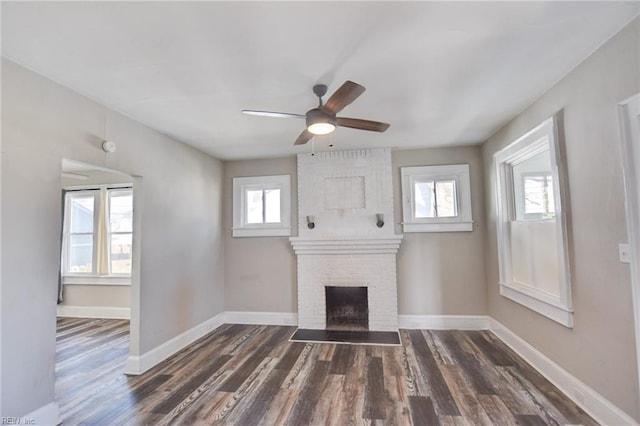 unfurnished living room with a ceiling fan, a fireplace, baseboards, and dark wood-style flooring