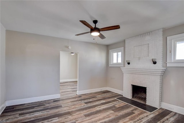 unfurnished living room featuring a wealth of natural light, baseboards, and wood finished floors