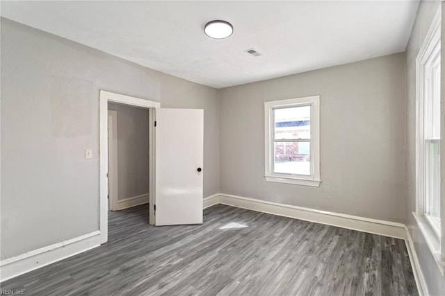 spare room featuring dark wood-style floors, baseboards, and visible vents