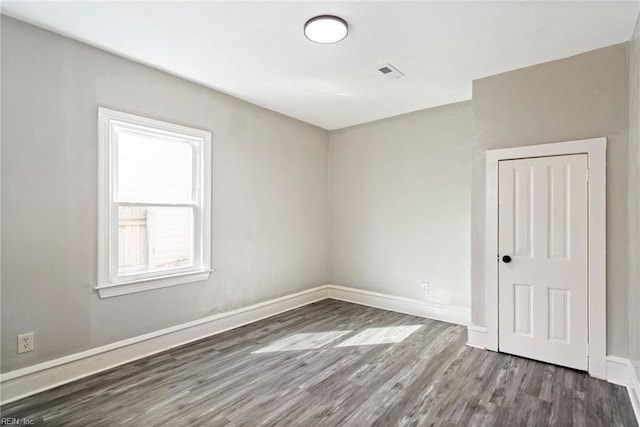 unfurnished room with visible vents, baseboards, and wood finished floors