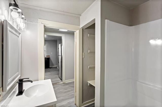 bathroom with wood finished floors, vanity, and baseboards