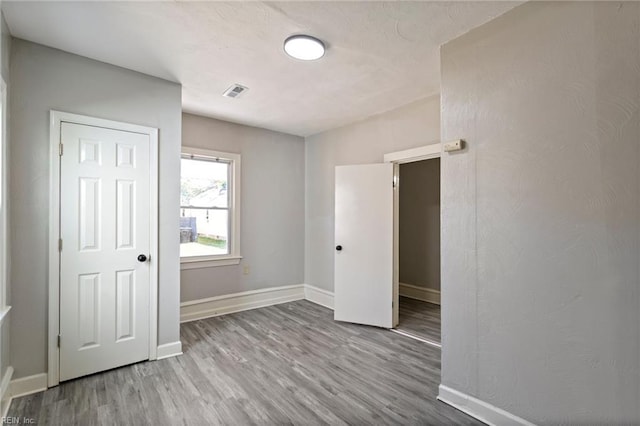 unfurnished bedroom with wood finished floors, visible vents, and baseboards