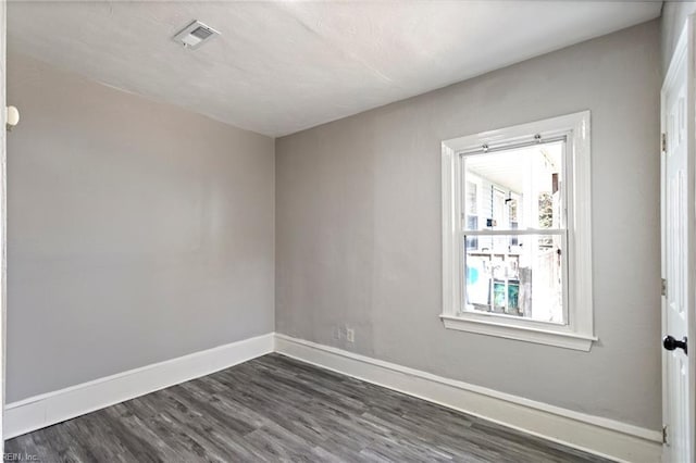 spare room with baseboards, visible vents, and dark wood-style flooring