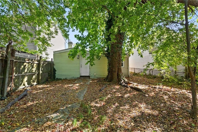 back of house featuring fence and an outdoor structure