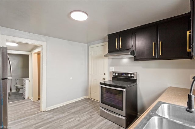 kitchen with light wood-style flooring, under cabinet range hood, a sink, baseboards, and appliances with stainless steel finishes