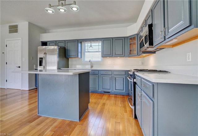 kitchen with stainless steel appliances, visible vents, a kitchen island, and light wood-style flooring